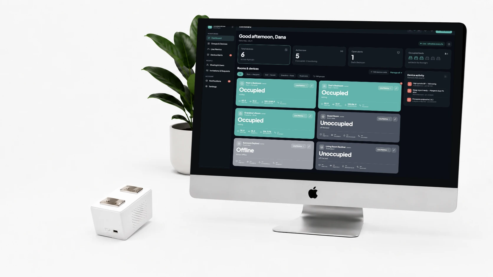 BedDot sensor on a desk beside an iMac showing the Cicada Sense dashboard