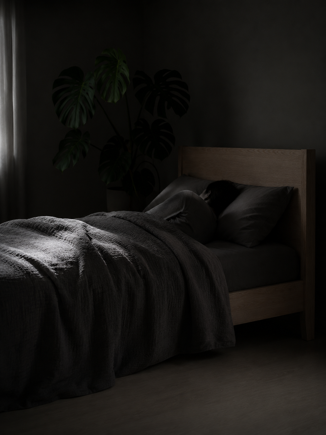 An adult asleep in a dark, calm bedroom